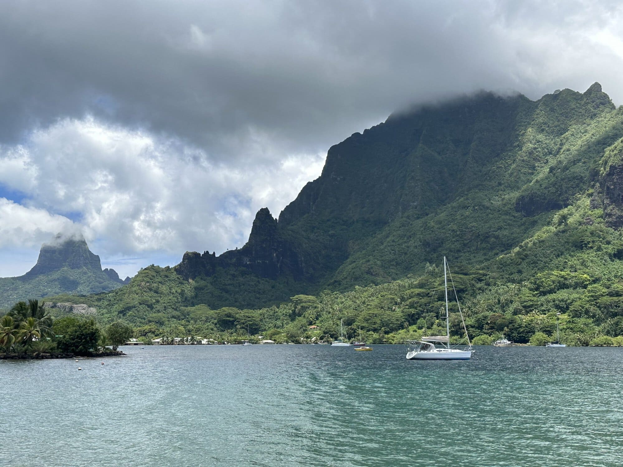 a sail boat anchored off the coast near mountains
