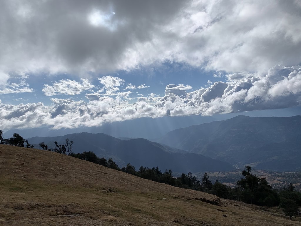 Brahmatal Trek in the Himalayas with cloudy sky and mountains in the distance