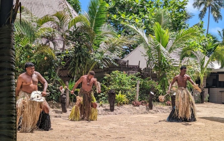 dancers in grass skirts performing a Traditional Fijian Dance