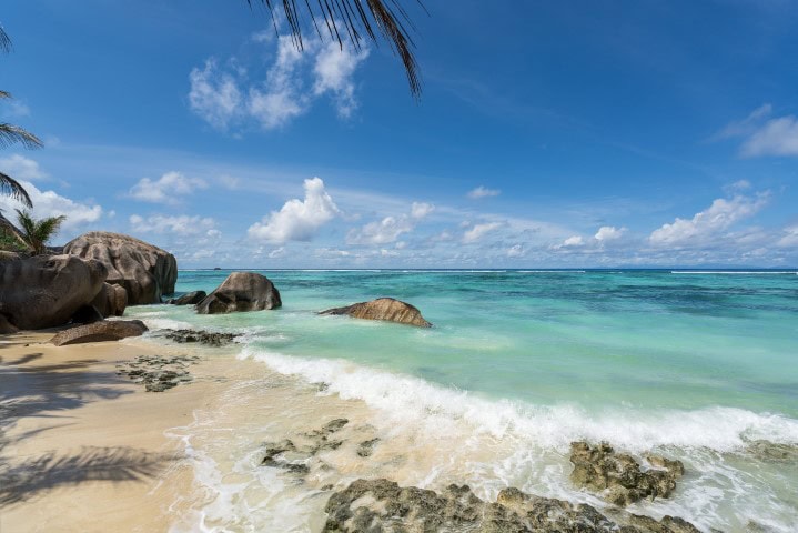 beach with boulders and aqua waters lapping the shore