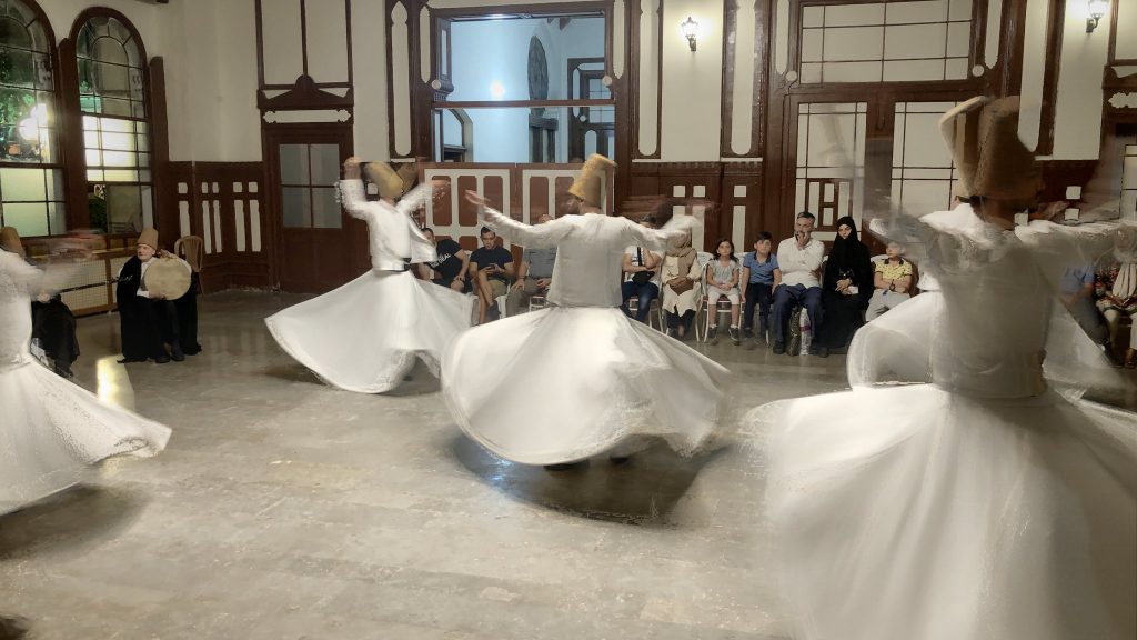 men dancing in long white cloaks spinning in circles
