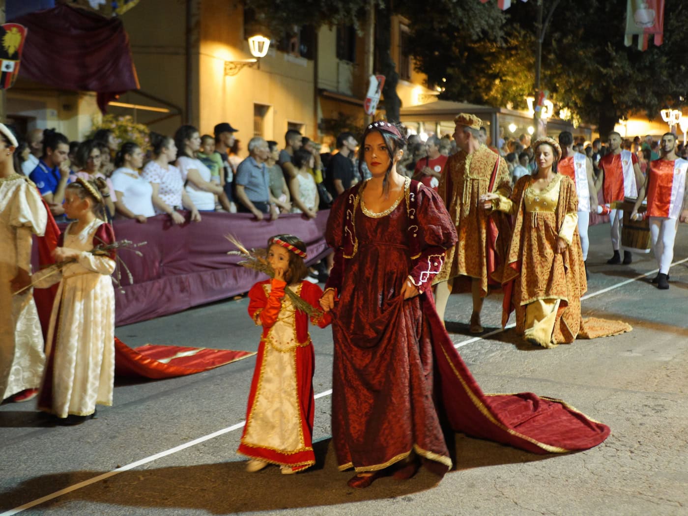 people dressed in traditional outfits walking down the street in a parade