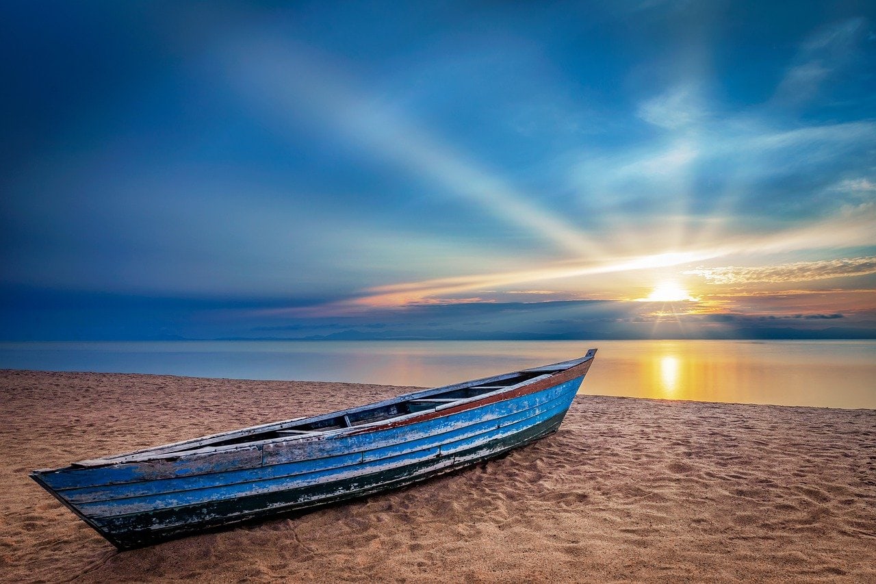 boat on shore of a lake with sun rising