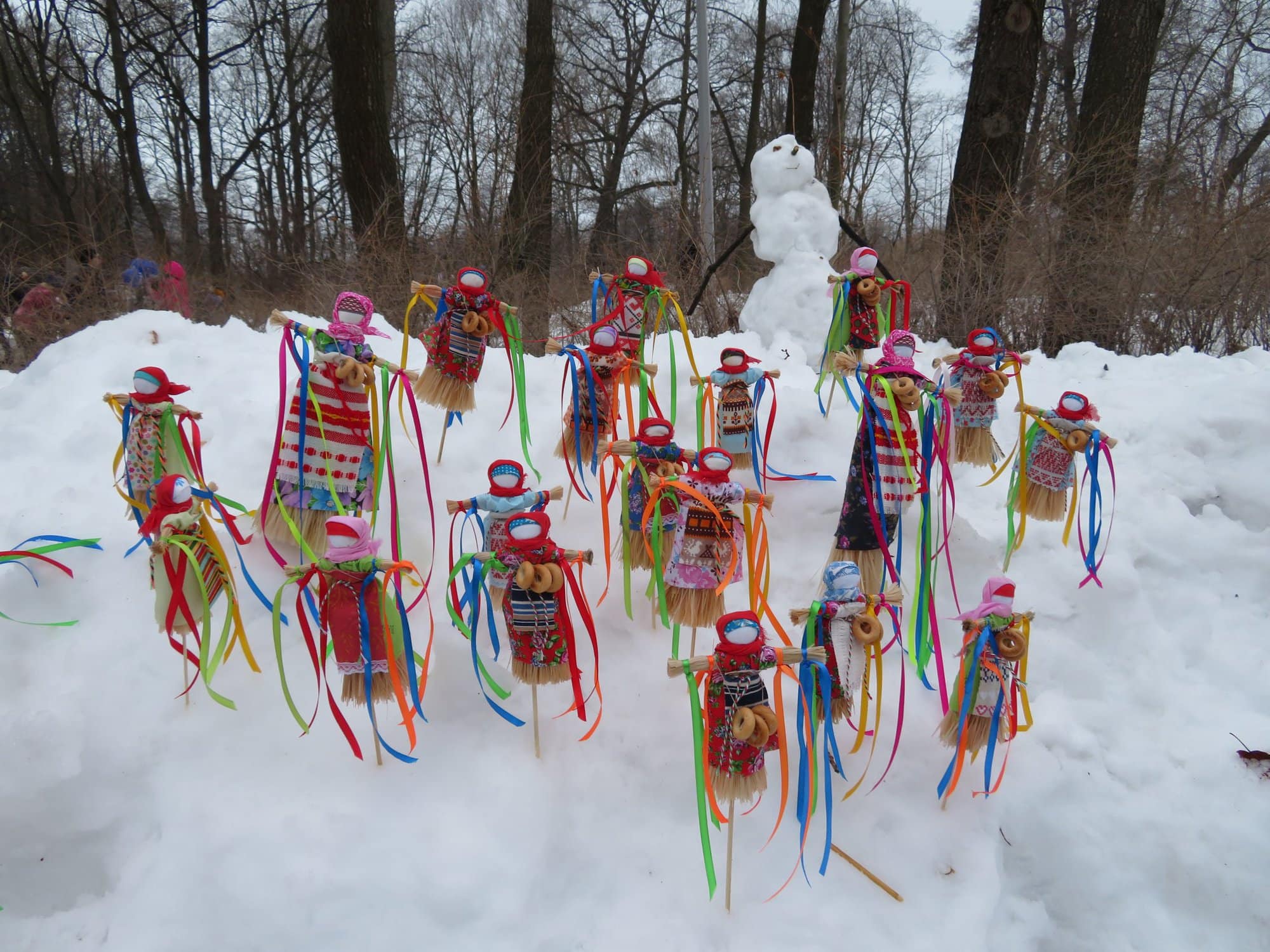 the March Festival of Maslenitsa in russia showing colourful dolls on sticks stuck in the snow