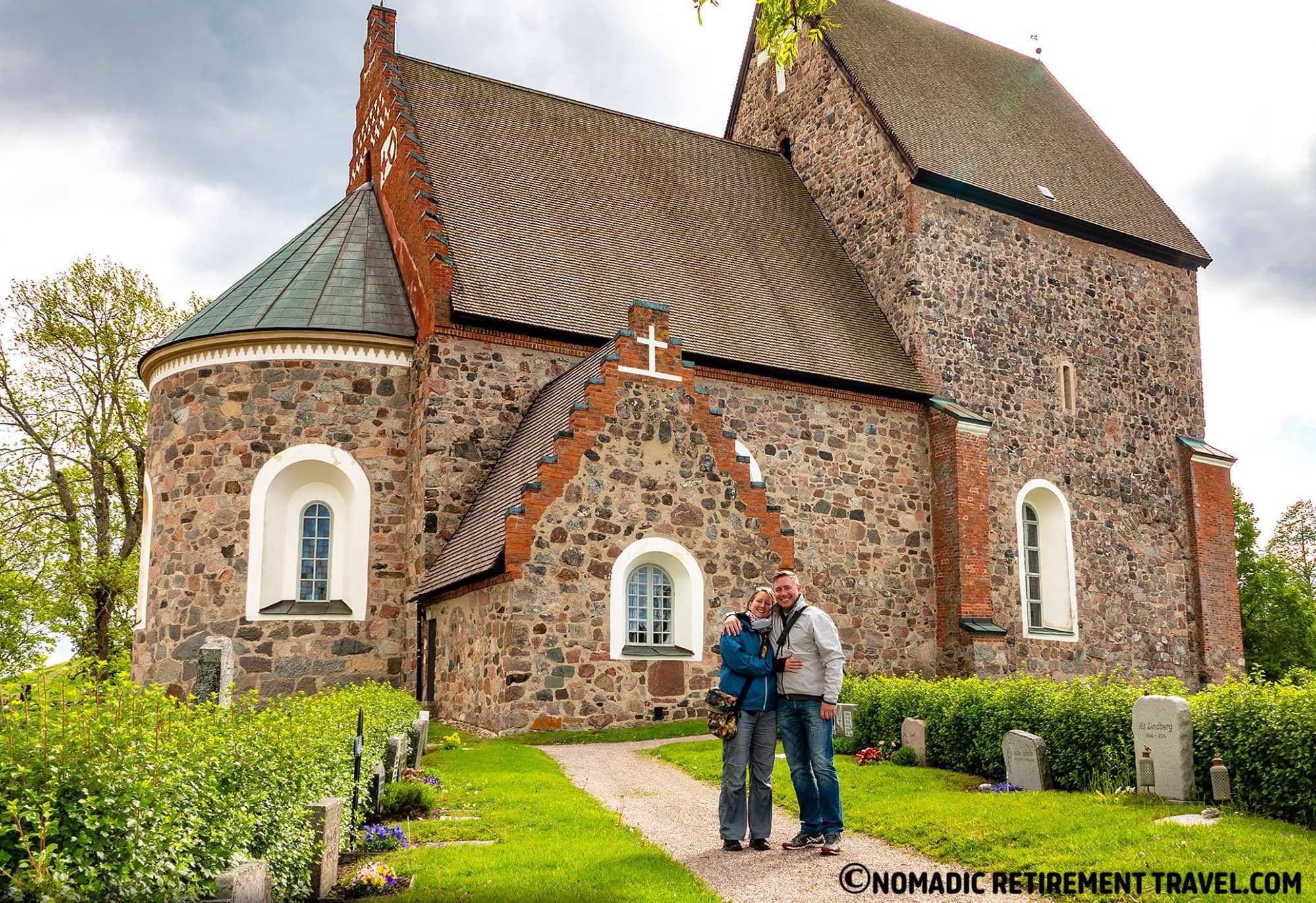 a couple standing in front of a very old church in sweden