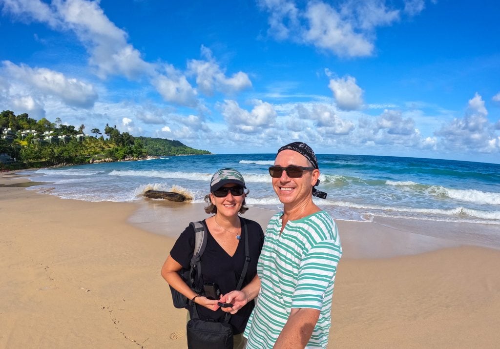 a couple on a beach in thailand with the sea behind them