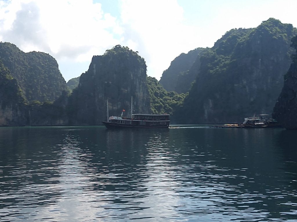 a bot set against limestone karts mountains in Vietnam