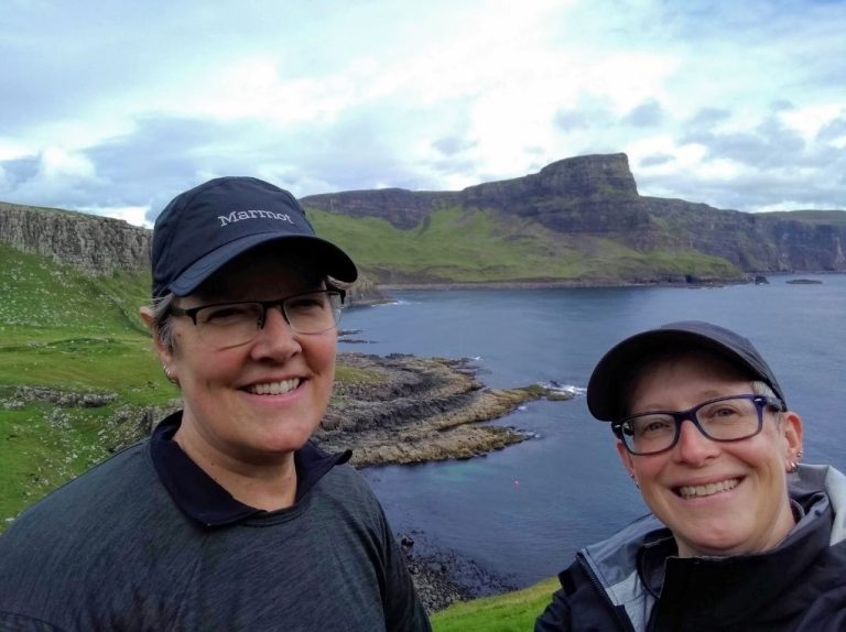 couple in front of water and green hills
