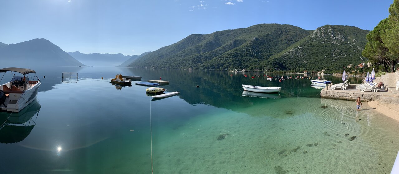 Bay of Kotor with boats on water and hills in distance in mist in Montenegro