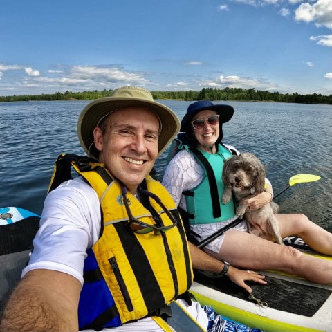 a couple in a canoe with a dog