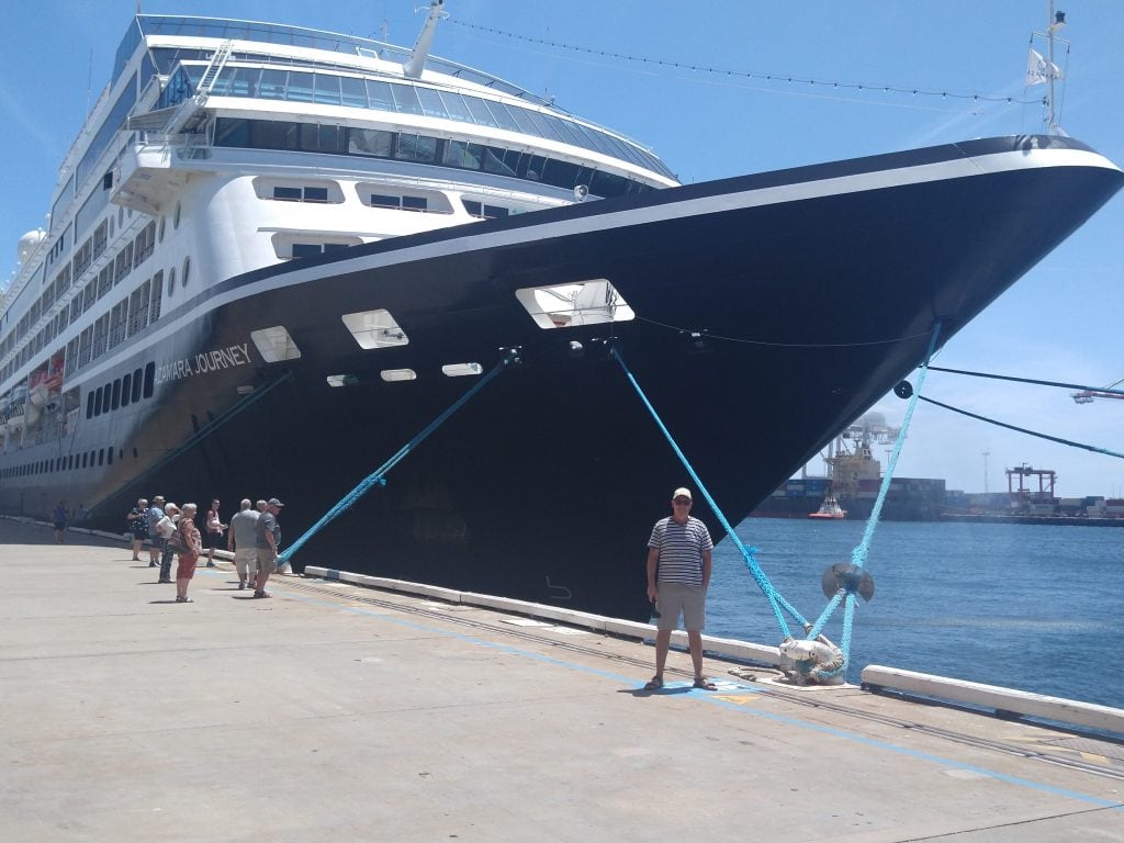 a man standing at the front of a large cruise ship in port