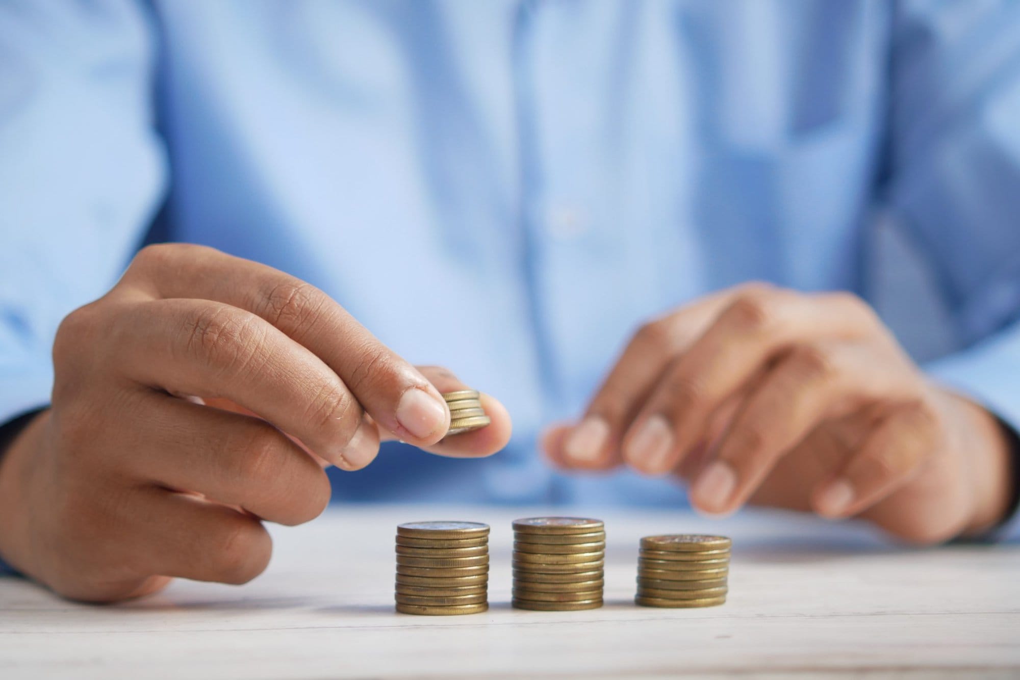 a mans hands placing coins on a table in 3 piles