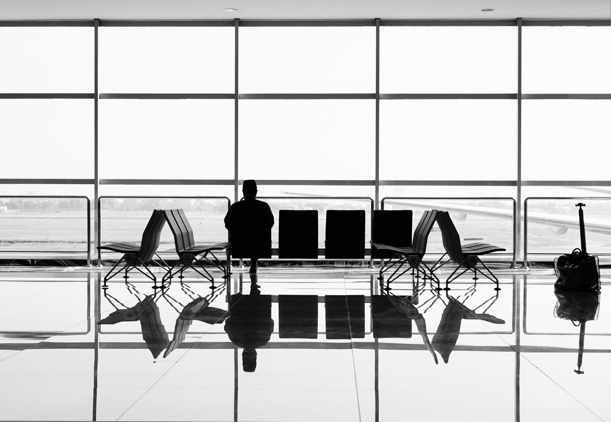 someone sitting at the windows in an airport overlooking the runway