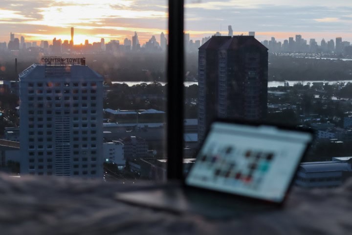 laptop on a desk in an apartment overlooking the city skyline at sunset