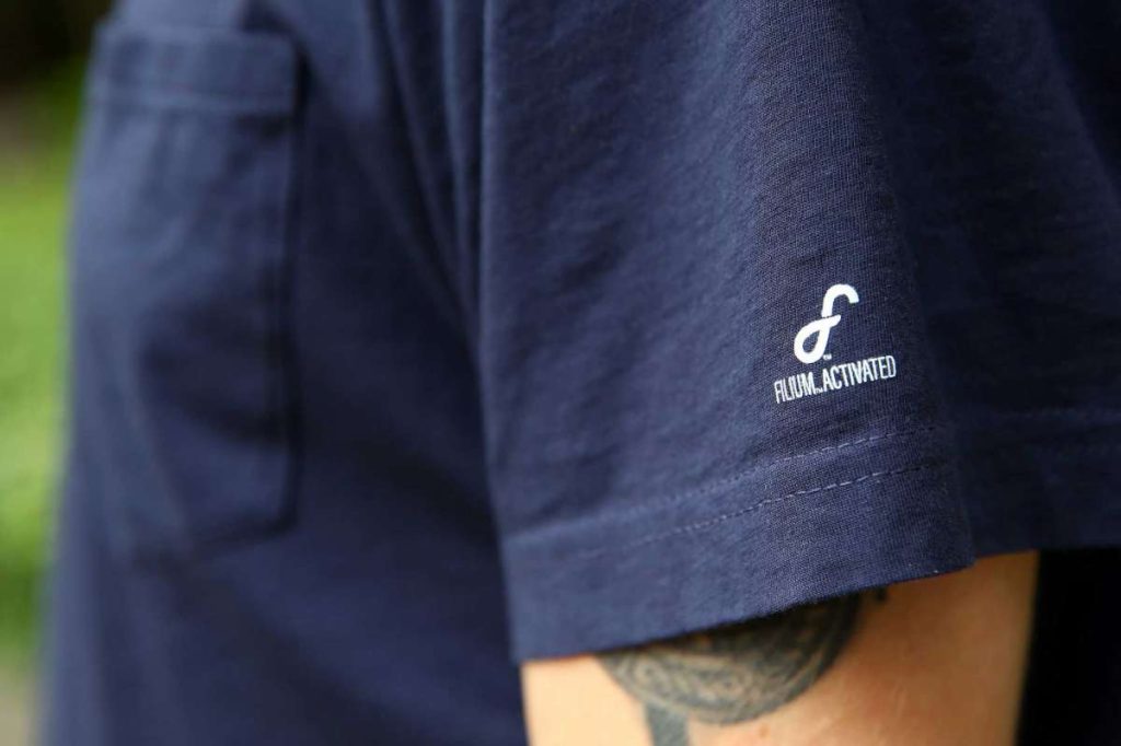 a picture of the sleeve of a navy blue Ably t-shirt with the Filium Activated logo