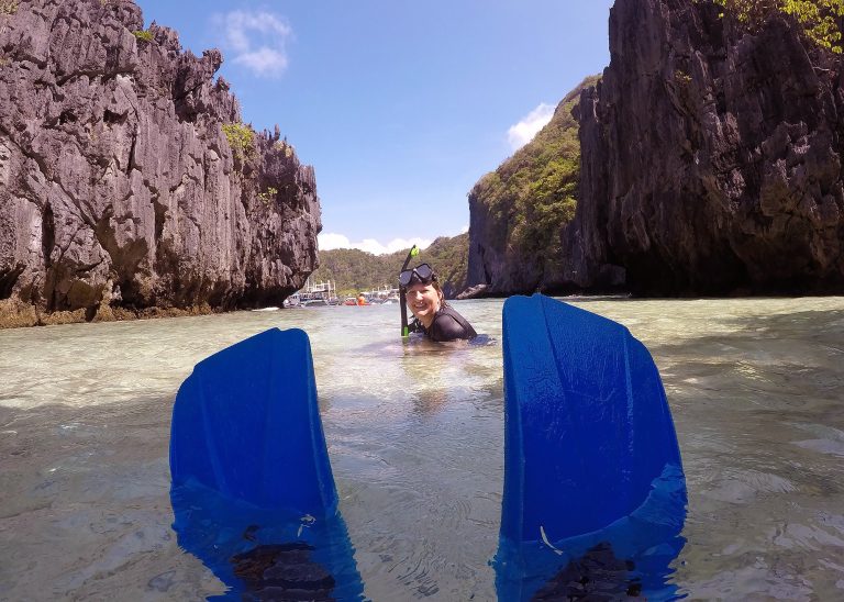 a photo of a woman in the water with a mask and snorkel on framed by the fins of the photographer