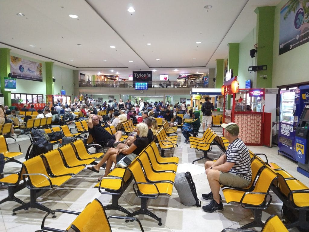 man waiting in a busy ferry terminal