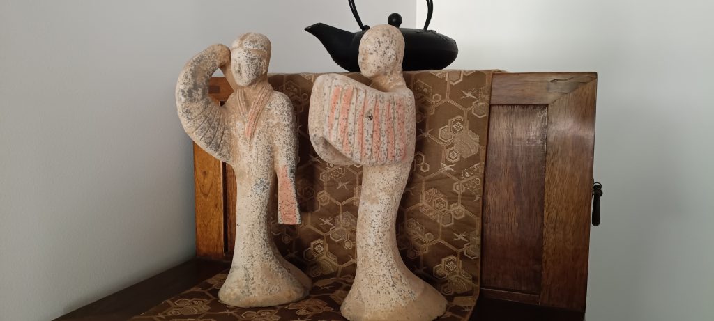 Two decorative figurines displayed on a wooden cabinet, symbolizing sentimental items considered when selling everything to travel.