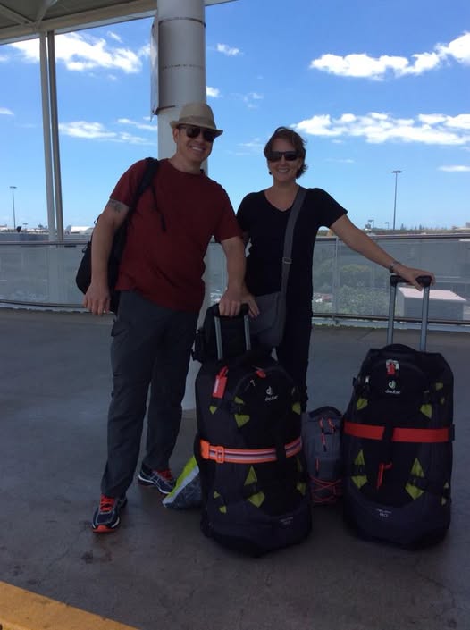 Nomadic retirement couple with rolling duffel bags at Brisbane Airport ready for a travel day.