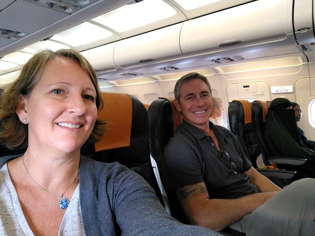 Nomadic retirement couple smiling on an airplane during a long travel day flight.