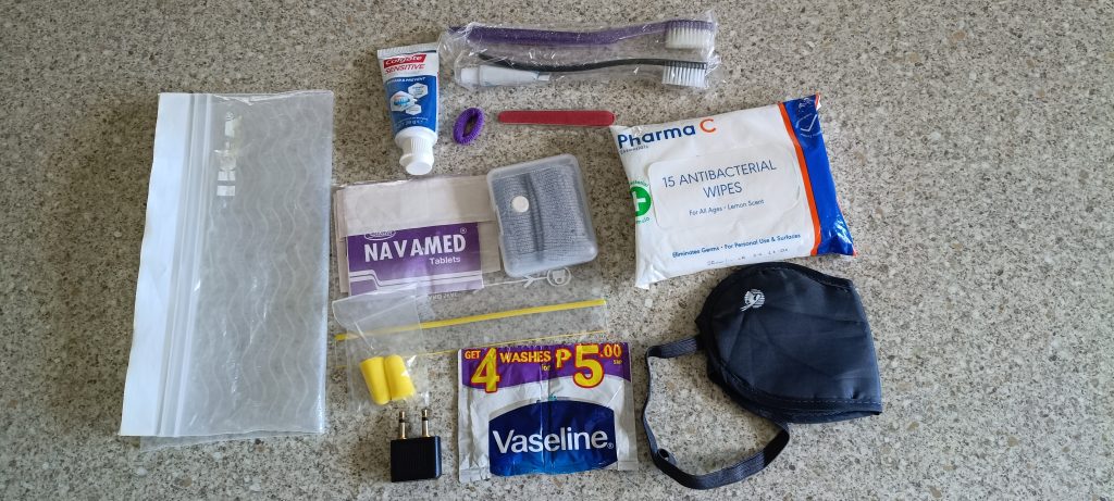 Mini travel day kit with toiletries, wipes, earplugs, adapter and small essentials for comfortable long travel days.