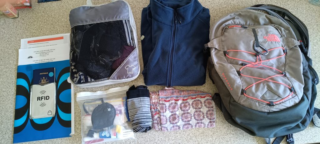 Travel day essentials laid out including passport, travel documents, packing cube, jacket and backpack for long-term travel.