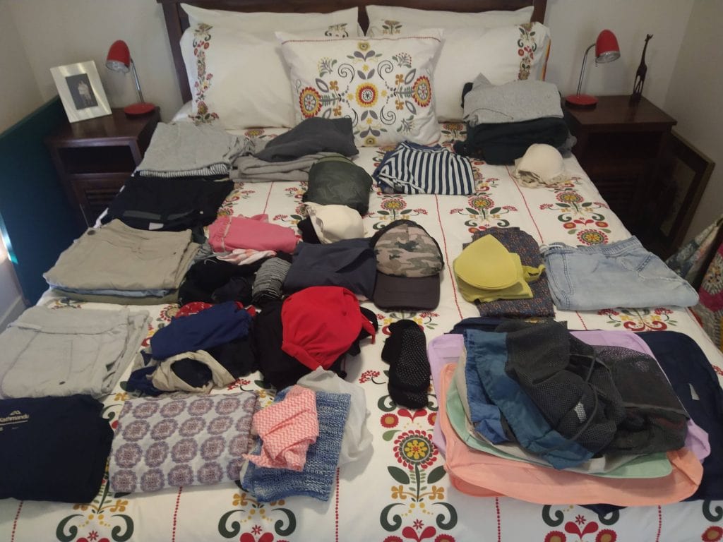 Clothing and travel items spread out before organising for long term travel packing