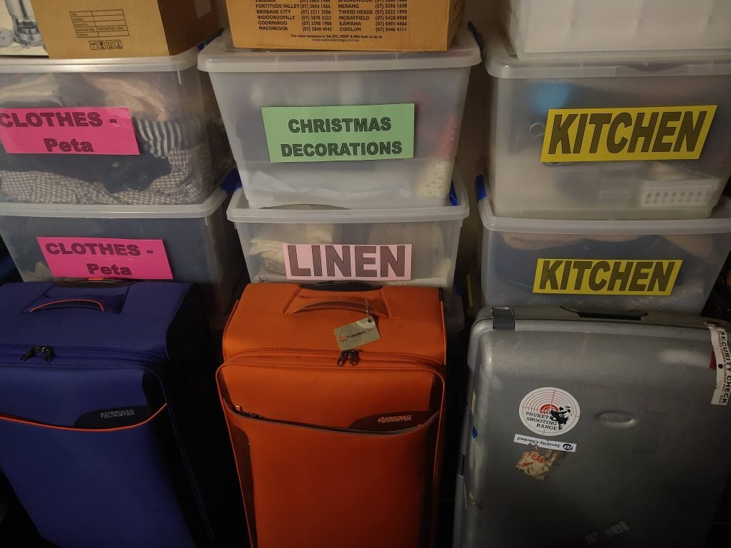 Decluttering and downsizing for travel with labeled storage boxes and suitcases ready for a nomadic lifestyle