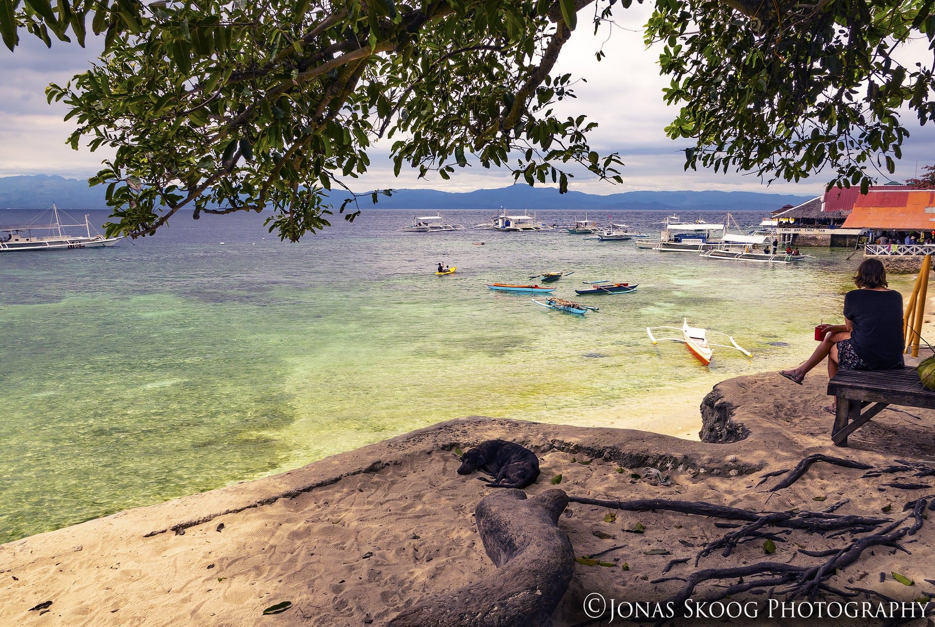 Relaxing by the beach during full-time travel lifestyle in a low-cost destination with boats and calm water