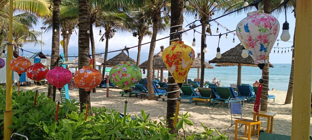 Colourful lanterns hanging on a beach in Da Nang with loungers and palm trees